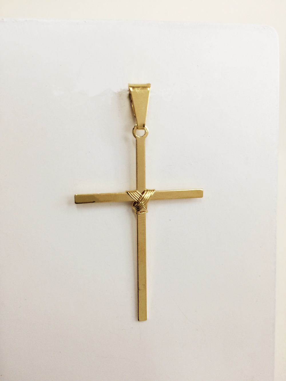 imagem Pingente Religioso de Cruz com detalhe de Amarra Banhado a Ouro 18k.